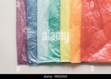 Wrinkled plastic bags in a row by the colors of the rainbow on light gray background. Stock Photo