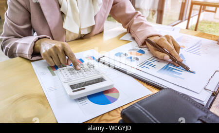 Business woman accountant working and calculating financial data on graph documents, doing finance in workstation. Stock Photo