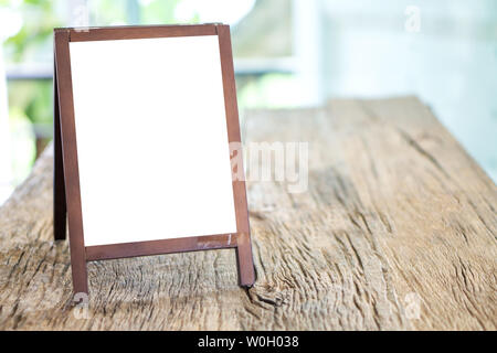 Mock up blank advertising whiteboard with easel standing on wood table in cafe and bar restaurant for display or montage of design space for text. Stock Photo