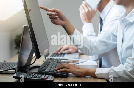 Stock exchange market concept, Team of investment trading or stock brokers having a consultation and analyzing with display screen and pointing on the Stock Photo