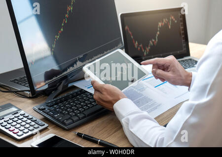 Stock exchange market concept, stock broker looking at graph working and analyzing with display screen, pointing on the data presented and deal on a e Stock Photo