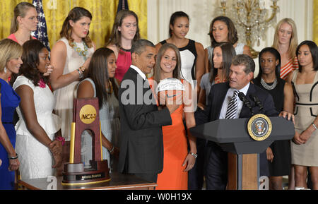 US President Barack Obama holds an autographed basketball presented by UConn's women's basketball head coach Geno Auriemma (at podium) as he welcomes the 2013 NCAA Champions to the White House, July 31, 2013, in Washington, DC. Obama continued a tradition of welcoming sports champions to the White House and thanking them for their community service.          UPI/Mike Theiler Stock Photo