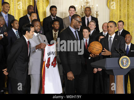 US President Barack Obama (R) accepts an autographed basketball from player LeBron James as Dwayne Wade holds an Obama jersey and Head Coach Erik Spoelstra (L) looks on, as the National Association (NBA) 2012 Miami ...