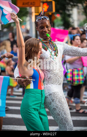 NEW YORK CITY - JUNE 25, 2017: A young caucasian woman dances with a tall transgender African-American woman at the gay pride parade in the Village. Stock Photo