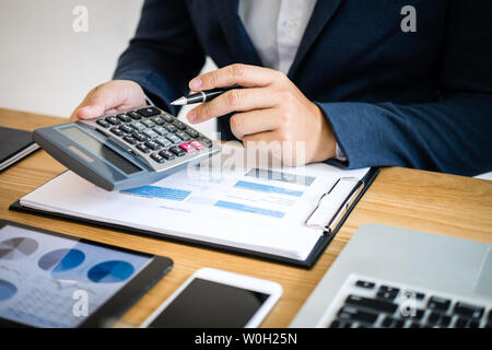 Businessman hands using text information on digital tablet to analyze financial statistical chart data and calculate cost of investment project. Stock Photo