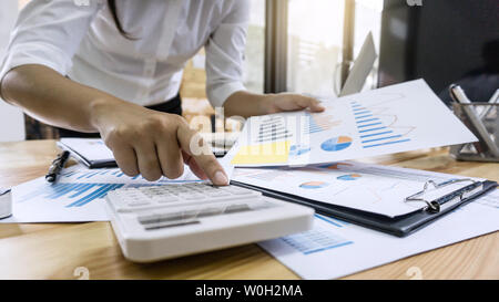 Business woman accountant working and calculating financial data on graph documents, doing finance in workstation. Stock Photo