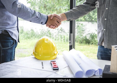 Shaking hands of collaboration, Construction engineering or architect discuss a blueprint while checking information on drawing and sketching, meeting Stock Photo