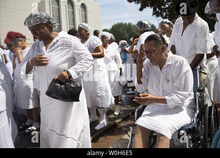 Women becomes emotional as they prey during a mass baptism by firehose at the United House of Prayer for All People on August 25, 2013 in Washington, D.C.  The church held the baptism following it's 87th Annual Holy Convocation.  UPI/Kevin Dietsch Stock Photo