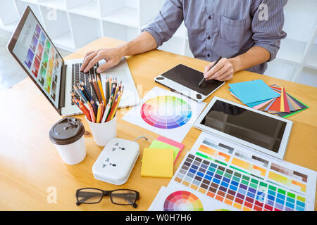 Young creative graphic designer working on project architectural drawing and color swatches, selection coloring on graphic chart with work tools and e Stock Photo