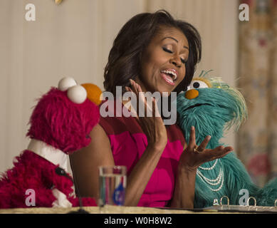 First Lady Michelle Obama joins with Sesame Street's Elmo and Rosita in an announcement to partner in a marketing campaign to help children eat healthier foods, at an event in the State Dining Room of the White House in Washington, DC on October 30, 2013.  The trio later joined children in the annual fall harvest of the White House Kitchen Garden.    UPI/Pat Benic Stock Photo