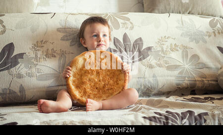 boy with uzbek cake on the couch at home Stock Photo