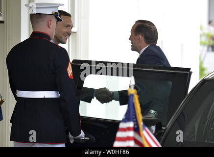 Australian Prime Minister Tony Abbott (R) is greeted by an unidentified protocol official as he arrives at the West Wing of the White House for a bilateral meeting with President Barack Obama, June 12, 2014, in Washington, DC. The two leaders are expected to discuss their trans-Pacific partnership, Australia's G-20 leadership and Asia-Pacific security issues.               UPI/Mike Theiler Stock Photo