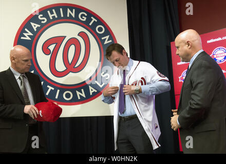 Washington Natioanls newly signed pitcher Max Scherzer puts on a jersey as  Washington Nationals Manager Matt Williams (L) and General Manager Mike  Rizzo watch during Scherzer introduction press conference at Nationals Park  in January 21, 2015