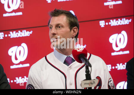 Washington Natioanls newly signed pitcher Max Scherzer puts on a jersey as  Washington Nationals Manager Matt Williams (L) and General Manager Mike  Rizzo watch during Scherzer introduction press conference at Nationals Park  in January 21, 2015