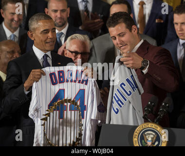 President Barack Obama smiles as Chicago Cubs first baseman Anthony Rizzo  presents him with a 'Chicago' jersey during a ceremony to honor the Cubs in  the East Room of the White House