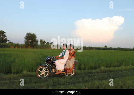 Indian rural couple riding on a motorcycle in the field Stock Photo
