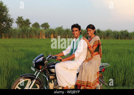 Indian rural couple riding on a motorcycle in the field Stock Photo
