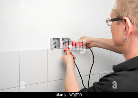 Electrician checks a socket outlet with a voltage indicator Stock Photo