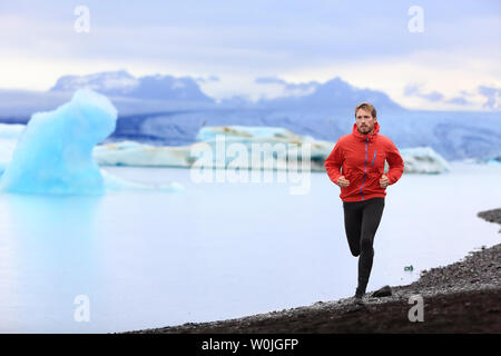 Running man. Trail runner training for marathon run in beautiful nature landscape. Fit male athlete jogging and cross country running by icebergs in Jokulsarlon glacial lake in Iceland. Stock Photo