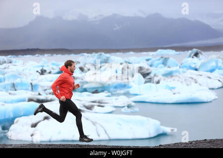 Running man. Sprinting trail runner in fast sprint in beautiful nature landscape. Fit male athlete sprinter cross country running by icebergs in Jokulsarlon glacial lake in Iceland. Stock Photo