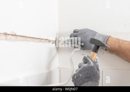 a craftsman punch a slit into a wall with a hammer and chisel Stock Photo