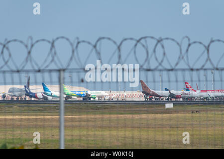 DENPASAR,BALI/INDONESIA-JUNE 08 2019: Some aeroplanes are parking and prepare for passengers to board, at Ngurah Rai Airport Bali. with the barbered w Stock Photo