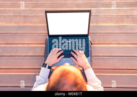 High angle view of businessman sitting on stairs and using blank screen laptop outdoors. Stock Photo