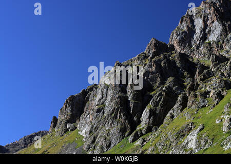 Rocky mountains of Alatau against piercing blue sky Stock Photo