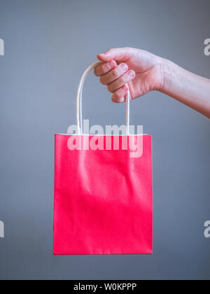 Hand holding red  bag for mockup blank template isolated on gray background Stock Photo