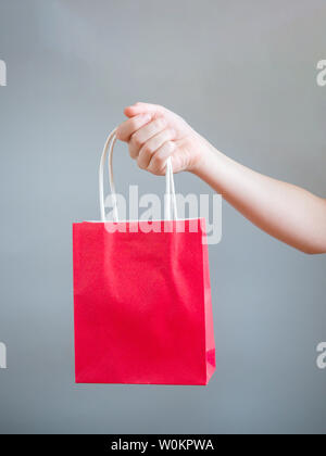 Hand holding red  bag for mockup blank template isolated on gray background Stock Photo
