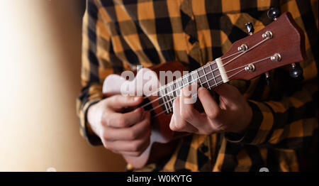 A young man playing ukulele in close up view Stock Photo