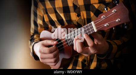 A young man playing ukulele in close up view Stock Photo