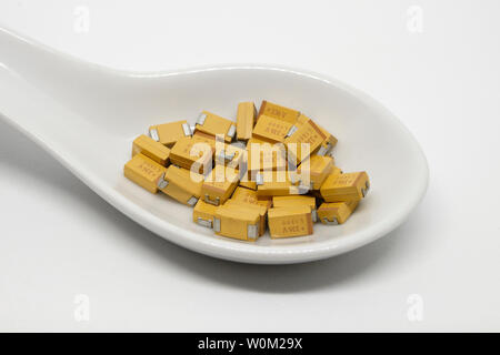 Tantalum chip surface mount capacitors on a ceramic spoon, electronic components Stock Photo