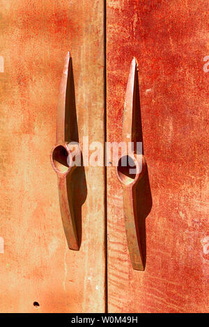 Two rusty metal doors with pick-axe heads for handles leading to the Courtyard Restaurant on Brewery Ave in downtown Bisbee, AZ Stock Photo