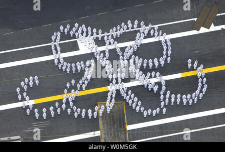 Sailors wearing summer white dress uniforms assemble on the ship's flight deck aboard USS Ronald Reagan (CVN 76) to form the double-R logo, honoring the former President Ronald Reagan, as the ship prepares to enter homeport of San Diego, Calif. , July 23, 2004.  (UPI Photo/Danielle Sosa/US Navy) Stock Photo