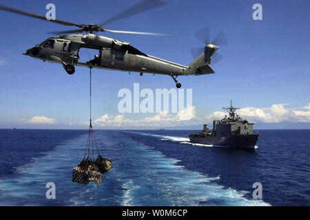 A U.S. Navy MH-60S Knighthawk helicopter transports cargo pallets to the dock landing ship USS Fort McHenry (LSD 43) during a vertical replenishment on January 14, 2005.  Helicopters and sailors assigned to the USS Abraham Lincoln (CVN 72) Carrier Strike Group are supporting Operation Unified Assistance, the humanitarian operation effort in the wake of the Tsunami that struck South East Asia. (UPI Photo/Jeremie Yoder/NAVY) Stock Photo