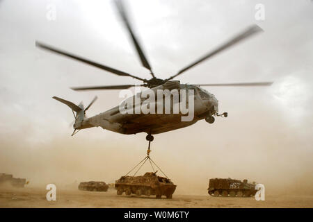 A CH-53E Super Stallion from Marine Heavy Helicopter Squadron 465 lifts an armored vehicle while moving it from the airfield at Al Asad, Iraq, to a test firing area May 2, 2005.   (UPI Photo/Juan Vara/U.S. Marine Corps) Stock Photo
