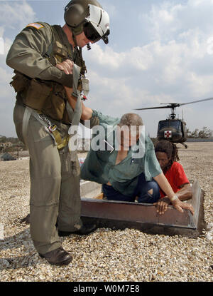 Maj. Timothy A. Doherty of the 148th  Medical Co. Georgia Army National Guard helps an elderly man up from a school building near downtown New Orleans on September 4. 2005 after being stranded by the flood waters that ravished the city.   (UPI Photo/ Brien Aho/USN) Stock Photo