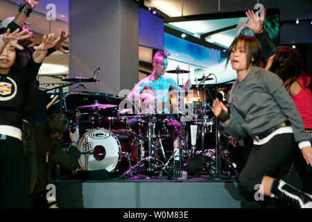 Blink182 drummer Travis Barker hammers away on his drum kit while dancers entertain the gathering at the Cadillac Escalade party at the North American International Auto Show in Detroit, Michigan on Sunday, January 8, 2006. Barker, star of the reality TV show 'Meet the Barkers,' was playing a set with DJ AM near the new 2007 Cadillac Escalade ESV and Escalade EXT. (UPI Photo/John F. MartinGM) Stock Photo