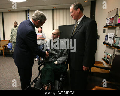 U.S. President George W. Bush (L) presents the Purple Heart to U.S. Army Spc. John C. Hoxie of Philippi, West Virginia during a visit to Walter Reed Army Medical Center in Washington on December 20, 2007. Hoxie is recovering from injuries suffered in Operation Iraqi Freedom. Looking on is the soldier's father, David Hoxie.  (UPI Photo/Joyce. N. Bogosian/White House Press Office). Stock Photo