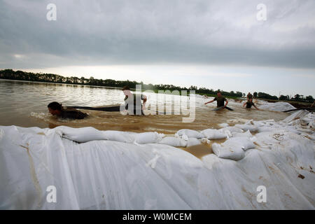 U.S. Marines and Sailors move a hose through water from the White River in Elnora, Indiana on June 9, 2008. Members of 26th MEU and U.S. Soldiers of the Indiana Army National Guard are helping state and local authorities raise the White River levee in an attempt to prevent further flooding in the area. (UPI Photo/Patrick M. Johnson-Campbell/U.S. Marine Corps) .. Stock Photo