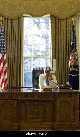 President Barack Obama talks on the phone at his desk in the Oval Office Wednesday morning, January 21, 2009, during his first full day in office. (UPI Photo/Pete Souza/White House) Stock Photo