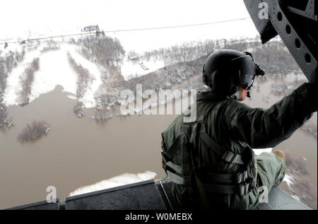 U.S. Army Staff Sgt. Jon Scarber, a flight engineer, looks out over the flooded Red River along the North Dakota/Minnesota border from a CH-47D Chinook helicopter on April 1, 2009. The Montana Army National Guard is assisting flood relief efforts and is conducting orientation flights to familiarize aviators and Soldiers with possible hazards in the region. (UPI Photo/Roger M. Dey/U.S. Army) Stock Photo