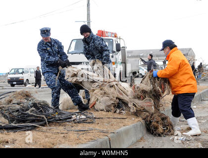 Sailors assigned to Naval Air Facility Misawa carries debris to a dumpsite during a cleanup effort at the Misawa Fishing Port, in Misawa, Japan, March 14, 2011. More than 90 Sailors from Naval Air Facility Misawa volunteered in the relief effort, assisting Misawa City employees and members of the community following the 8.9 magnitude earthquake and tsunami that devastated the country. UPI/Devon Dow/U.S. Navy. Stock Photo