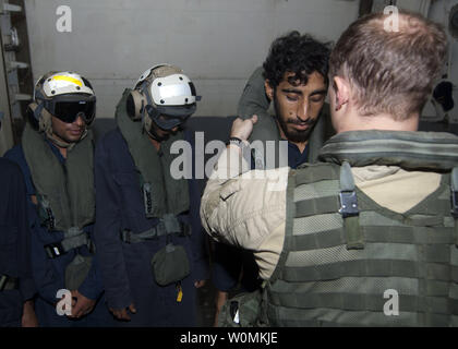 Sailors assigned to the guided-missile destroyer USS James E. Williams (DDG 95) instruct rescued Iranian mariners on how to properly wear protective equipment before being transported by helicopter to the aircraft carrier USS Enterprise (CVN 65), in the Gulf of Oman, August 9, 2012. Ten Iranian Mariners were rescued after they were forced to abandon their vessel, which caught fire in the Gulf of Oman. UPI/Daniel Meshel/US Navy. Stock Photo