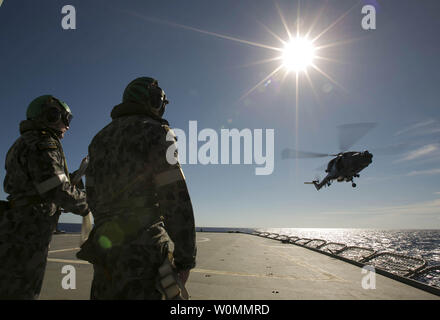 Crew members aboard the Australian Navy ship HMAS Success watch as a helicopter participates in a Replenishment at Sea with the Royal Malaysian Navy ship KD LEKIU in the southern Indian Ocean during the continuing search for  Malaysia Airlines jetliner missing in the Indian Ocean, about 1,000 miles off the coast of Perth, Australia.  The U.S. Navy 'towed pinger locator' connected to the Ocean Shield picked up signals consistent with that of the missing jetliner it was announced today April 7, 2014.   UPI/ David Connolly/Australian Defense Force Stock Photo