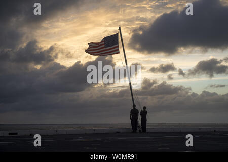 Sailors haul down the American flag aboard the amphibious transport dock ship USS Mesa Verde (LPD 19) at sunset on October 5, 2016, while the ship loads food, first aid, and medical supplies. Mesa Verde is underway in preparation to support humanitarian assistance and disaster relief efforts in Haiti in response to Hurricane Matthew. Photo by Joshua M. Tolbert/U.S. Navy/UPI Stock Photo