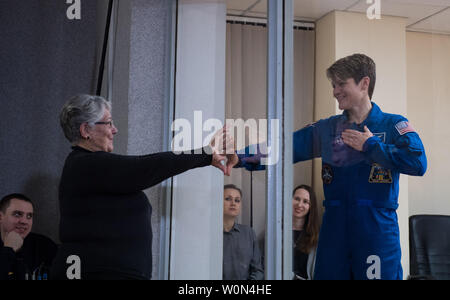 Expedition 58 Flight Engineer Anne McClain of NASA,  who is in quarantine, puts her hand up to the glass to meet her mother at the conclusion of a press conference, on December 2, 2018, at the Cosmonaut Hotel in Baikonur, Kazakhstan. Launch of the Soyuz rocket is scheduled for Dec. 3 that will carry McClain, Soyuz Commander Oleg Kononenko of Roscosmos, and Flight Engineer David Saint-Jacques of the Canadian Space Agency (CSA) into orbit to begin their six and a half month mission on the International Space Station. NASA Photo by Aubrey Gemignani/UPI Stock Photo