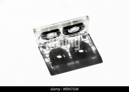 Transparent plastic C90 compact cassette audio tape casting a shadow against a white background Stock Photo