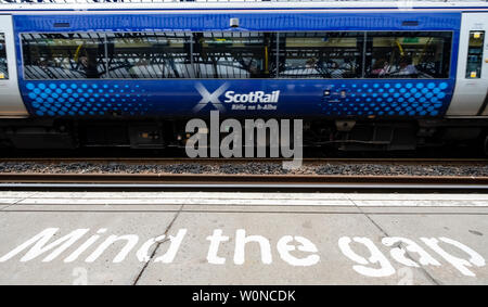 View of Scotrail passenger train at station platform with Mind the Gap warning painted on edge, Stirling, Scotland, UK Stock Photo